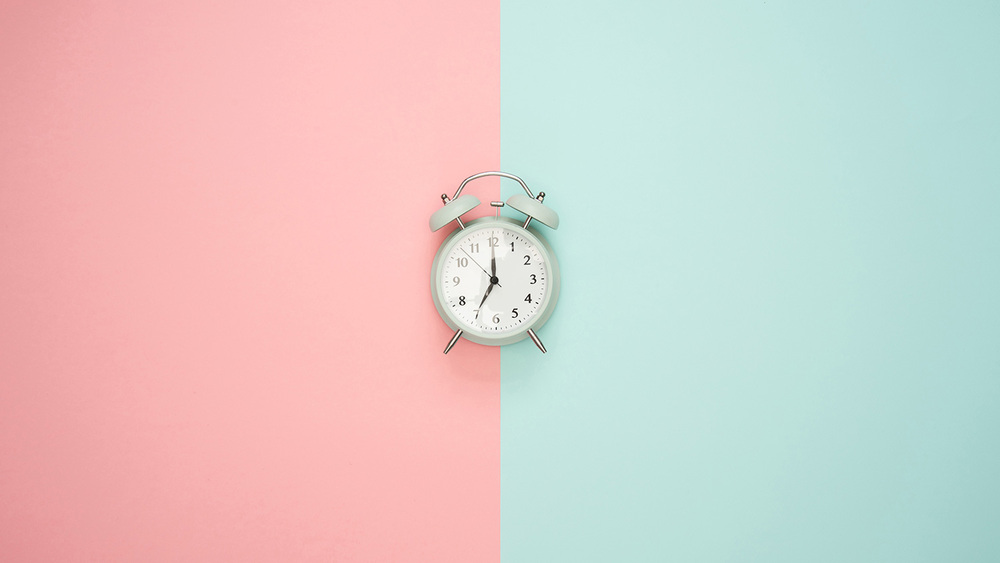 Alarm clock on a split blue and pink pastel colour background 